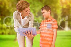 Composite image of teacher showing tablet to pupil at library