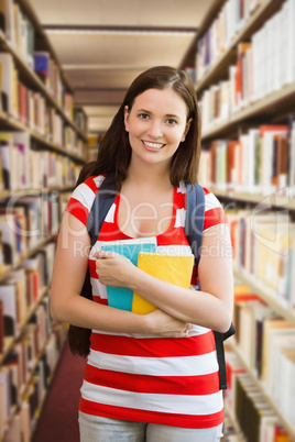 Composite image of student smiling at camera in library Composite image of student smiling at camera in library