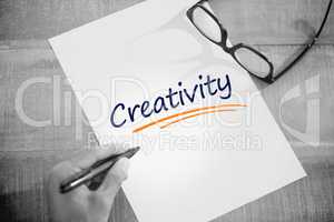 Creativity  against left hand writing on white page on working d