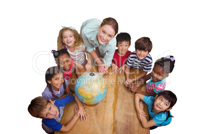 Composite image of cute pupils smiling around a globe in classro