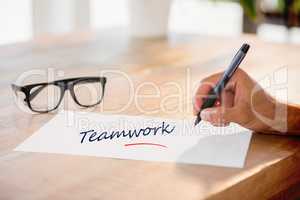 Teamwork against side view of hand writing on white page on work