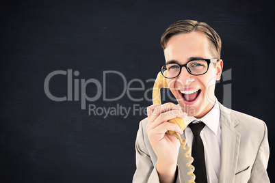 Composite image of geeky businessman talking on retro phone