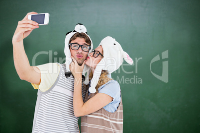 Composite image of geeky hipster couple taking selfie with smart