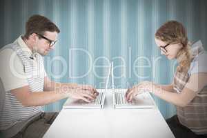 Composite image of geeky hipster couple using laptop