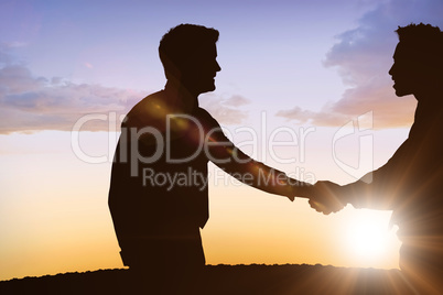 Composite image of silhouettes shaking hands
