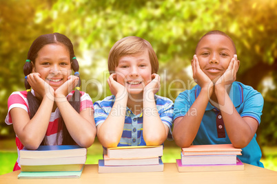 Composite image of cute pupils looking at camera in library