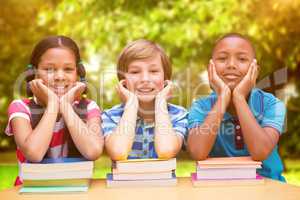 Composite image of cute pupils looking at camera in library