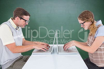 Composite image of geeky hipster couple using laptop