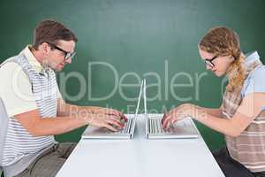 Composite image of geeky hipster couple using laptop