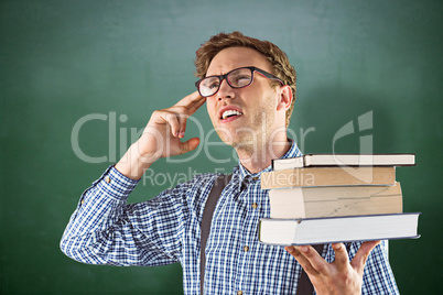 Composite image of geeky student holding a pile of books