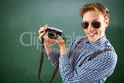 Composite image of geeky hipster holding a retro camera