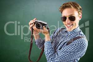 Composite image of geeky hipster holding a retro camera