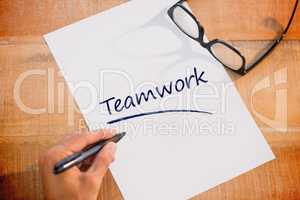 Teamwork against left hand writing on white page on working desk