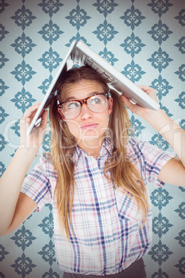 Composite image of geeky hipster holding her laptop over her hea