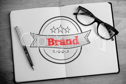 Brand against overhead of open notebook with pen and glasses