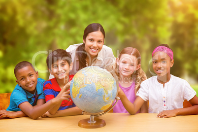 Composite image of cute pupils and teacher looking at globe in l