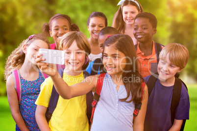 Composite image of cute pupils using mobile phone