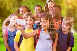 Composite image of cute pupils using mobile phone