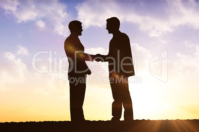 Composite image of silhouettes shaking hands