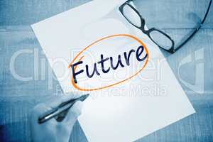 Future against left hand writing on white page on working desk