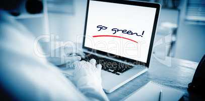 Go green! against businessman working on his laptop