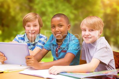 Composite image of cute pupils using tablet computer in library