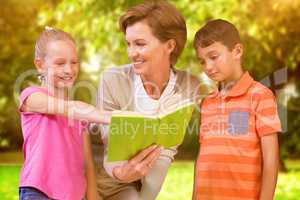 Composite image of teacher reading book with pupils at library