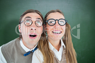 Composite image of geeky hipster couple raising eyes