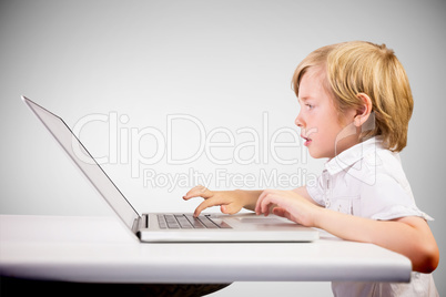 Composite image of cute boy using laptop