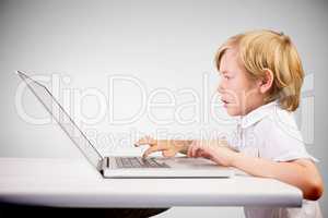 Composite image of cute boy using laptop