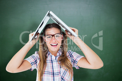 Composite image of geeky hipster holding her laptop over her hea