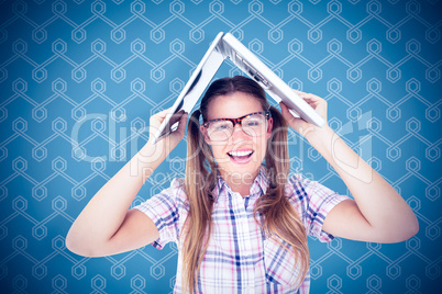 Composite image of geeky hipster holding her laptop over her hea