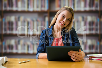 Composite image of student studying in the library with tablet