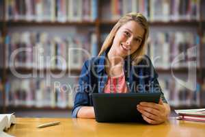 Composite image of student studying in the library with tablet