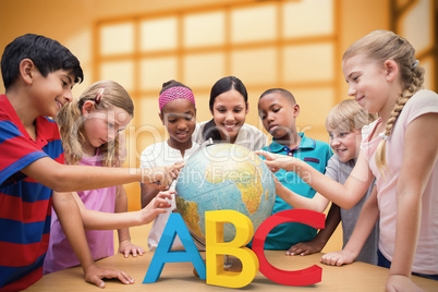 Composite image of cute pupils and teacher looking at globe in l