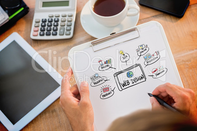 Composite image of man writing on clipboard on working desk