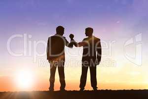 Composite image of silhouettes shaking hands