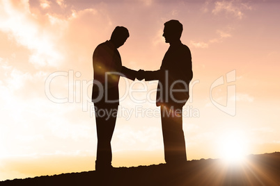 Composite image of silhouettes shaking hands