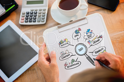 Composite image of man writing on clipboard on working desk