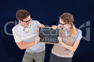 Composite image of geeky hipster couple holding little blackboar