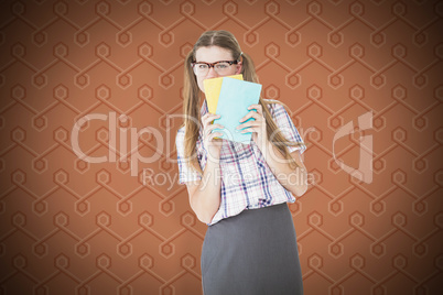 Composite image of geeky hipster hiding her face behind notepad