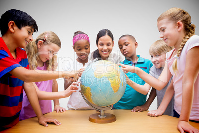 Composite image of cute pupils and teacher looking at globe in l