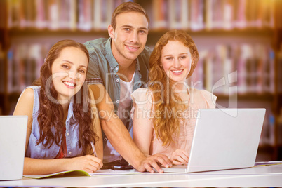 Composite image of fashion students using laptop