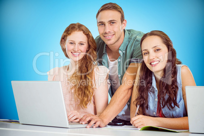 Composite image of fashion students using laptop