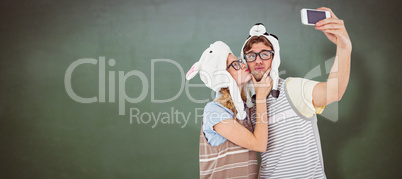 Composite image of geeky hipster couple taking selfie with smart