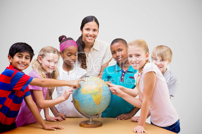 Composite image of cute pupils and teacher looking at globe in l