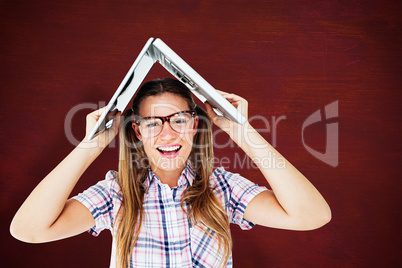 Composite image of geeky hipster holding her laptop over her hea