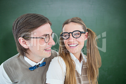 Composite image of geeky hipster couple smiling at each other