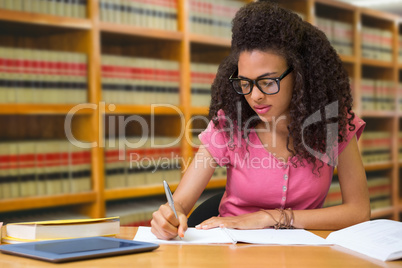 Composite image of student sitting in library writing