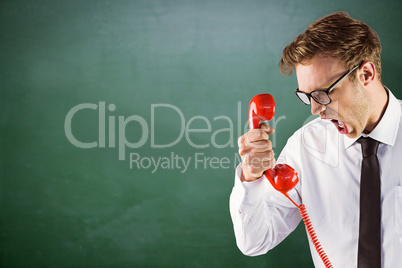 Composite image of angry geeky businessman holding telephone